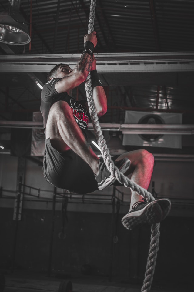 Photo of athlete performing rope climbs in the gym.